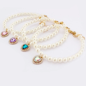 Detail of four pearl pet necklaces with heart pendants in pink, purple, teal and white colors
