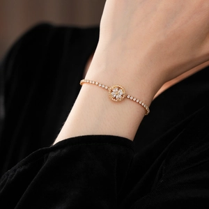 Close-up of a gold clover bracelet with sparkling zircons worn on a female wrist