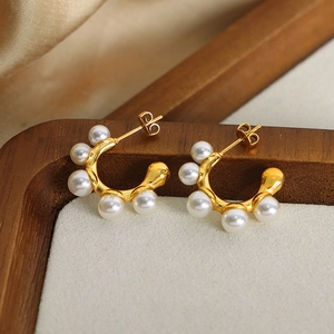 French vintage C-shaped gold plated earrings with white pearls on a luxury wooden tray