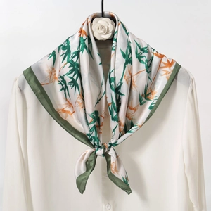 Detail of silk-like scarf with green bamboo print styled on a white shirt collar