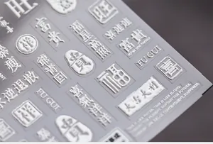 Close-up of 3D embossed silver nail art stickers with metallic Chinese characters