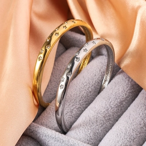 Detailed macro view of gold and silver star-studded zircon bangles on grey velvet