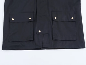 Detail of black hooded windbreaker showing flap pockets and golden metal buttons
