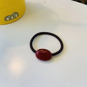Detail of dark red oval bead on black elastic hair tie for a stylish ponytail look