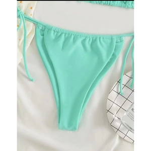 Close-up of mint green tie-side bikini bottoms with high-cut design on white fabric