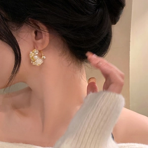 Elegant gold hoop earrings with white pearls and sparkling crystals on model