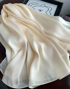 Detail of elegant cream satin scarf with smooth glossy texture and draped pleats