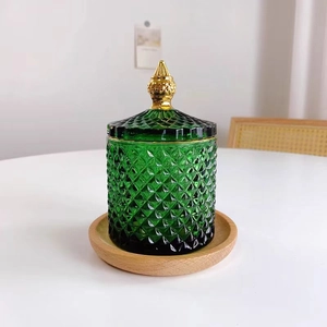 Grünes Vorratsglas mit Diamantstruktur und Golddeckel auf dem Holztablett