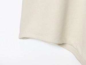 Detailed close-up showing high-quality double-stitch sewing on beige knit fabric