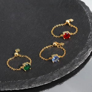 Detailed shot of adjustable gold chain rings with red, blue, and green gemstones