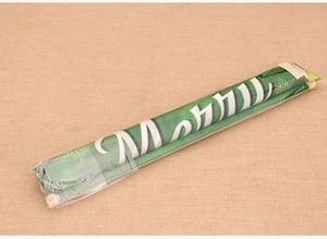 Close-up of a rolled green Merry Christmas hanging scroll wrapped in protective plastic film