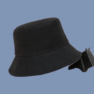 Side view of minimalist black cotton canvas bucket hat against a solid blue background