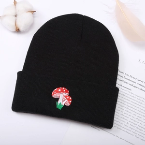 Unisex black knit beanie featuring a red mushroom embroidery on a minimalist white setting