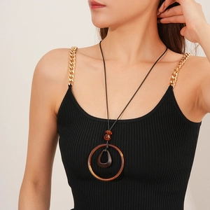 Detail view of long wax cord necklace with geometric resin pendant on a model