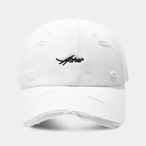 Detailed view of white distressed baseball cap with vintage embroidery and torn fabric