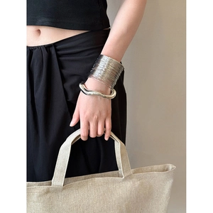 Close-up of chunky silver irregular metal bangles worn for a minimalist aesthetic