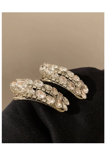 Macro shot of two sparkling rhinestone hair clips on dark fabric showing intricate details