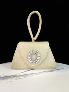 Detailansicht der goldenen Abendtasche mit Glitzerfinish und funkelnder Strassschnalle