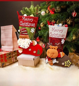 Close-up of fabric Christmas stockings with Santa and reindeer plush figures and embroidery