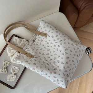 Détail d'un sac fourre-tout en lin floral rouge avec poignées en cuir et rivets en métal