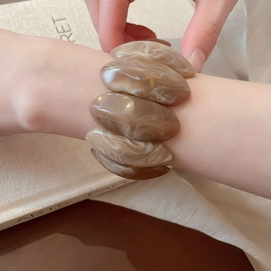 Detailed macro view of an amber marble resin stretch bracelet worn on a wrist