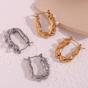 Detailed macro shot of U-shaped gold and silver earrings with pearls and water drops