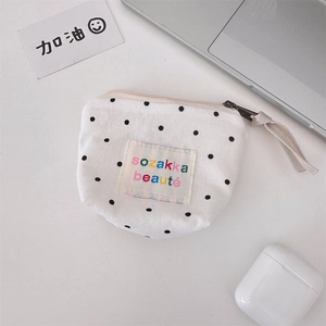 Close-up of white canvas polka dot makeup pouch with zipper on a desk with accessories