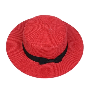 Close-up of red straw sun hat featuring a wide brim and black bow ribbon decoration