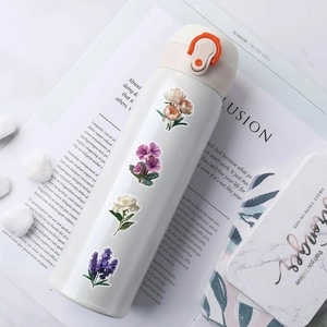 White stainless steel vacuum flask with floral stickers on a magazine background