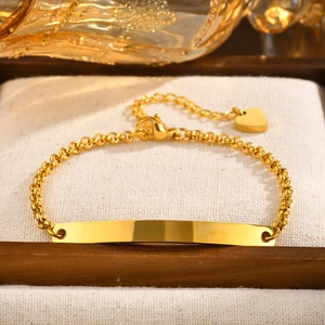 Detail of gold stainless steel pearl chain bracelet with customizable curved bar and heart charm
