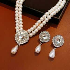 Detailed view of double-layer pearl necklace and crystal earrings set on leather background
