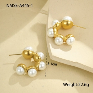 Detail of C-shaped stainless steel earrings with gold beads and white pearls on stone