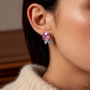 Close-up of pink gemstone stud earrings with leaf detailing on model in soft lighting