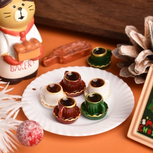 Detailed macro shot of five miniature Christmas coffee cups with gold trim on a white saucer