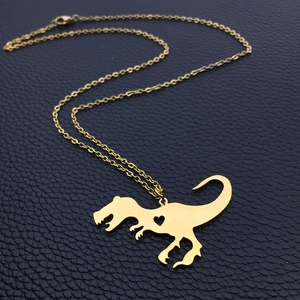 Collana con silhouette di T-Rex dorata e cuore traforato su catena lucida a croce