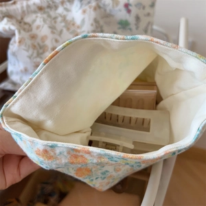 Vue détaillée montrant la doublure douce en velours crème d'un pochon à fleurs chic
