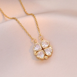Macro detail of gold four-leaf clover necklace with sparkling heart-shaped zircons on silk