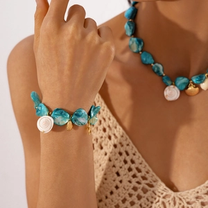 Detail of beach style stainless steel necklace and bracelet with shells and blue beads