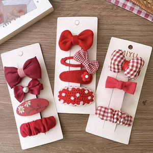 Festive red fabric bow and flower hair clips set for girls on white card background