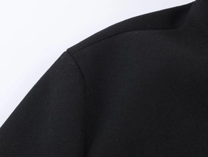Close-up of black woolen coat shoulder showing high-quality stitching and fabric texture