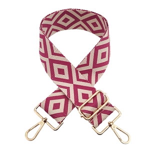 Macro view of geometric jacquard wide bag strap with golden hardware and pink diamond pattern