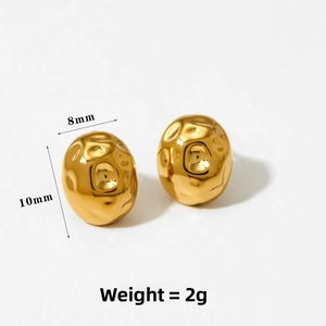 Macro view of gold textured oval stud earrings showing detailed hammered metal surface