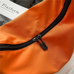 Orange nylon crossbody dumpling bag with smooth dual black zippers and texture