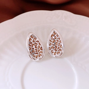 Macro shot of silver stud earrings with teardrop leopard print on a ceramic tray