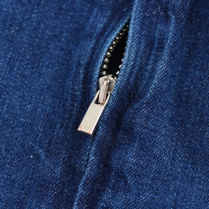 Dettaglio della cerniera metallica su un abito lungo a fascia in denim blu vintage