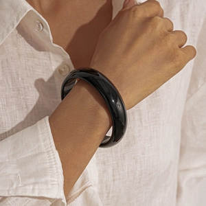 Close-up of a thick black resin bangle with glossy finish on a model's wrist