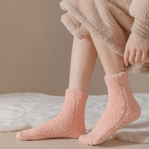 Close-up of soft pink coral fleece five-finger socks on a white plush carpet background