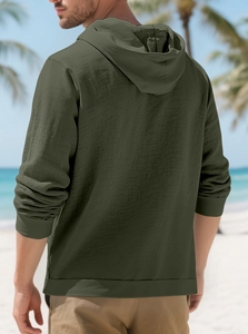 Rear view of an olive green hooded linen shirt with textured fabric in a beach setting