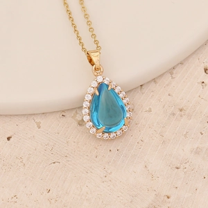 Macro view of gold teardrop necklace featuring a blue gemstone and sparkling zircons