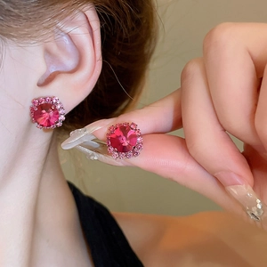Close-up of pink crystal stud earrings with a halo design worn by a model for detail